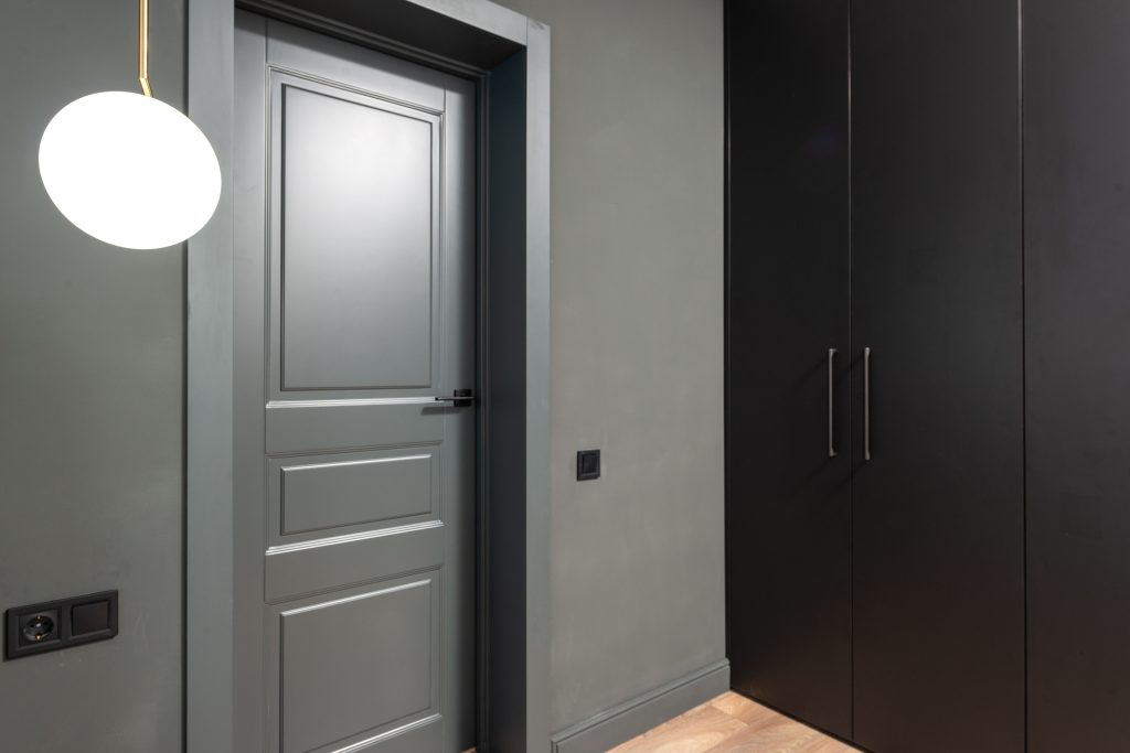 Stylish interior with a minimalist wardrobe, grey door, and modern lighting fixture.